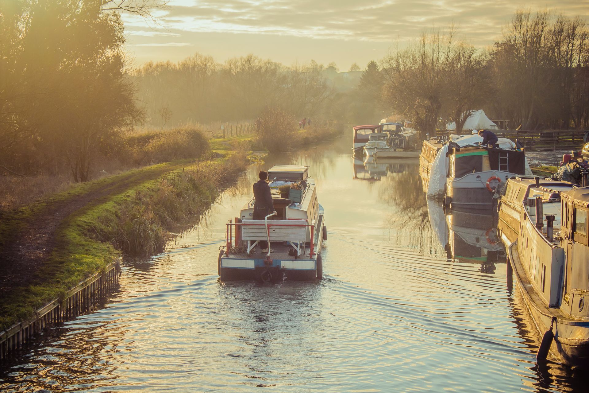 A canal boat drifting along a still waterway at golden hour