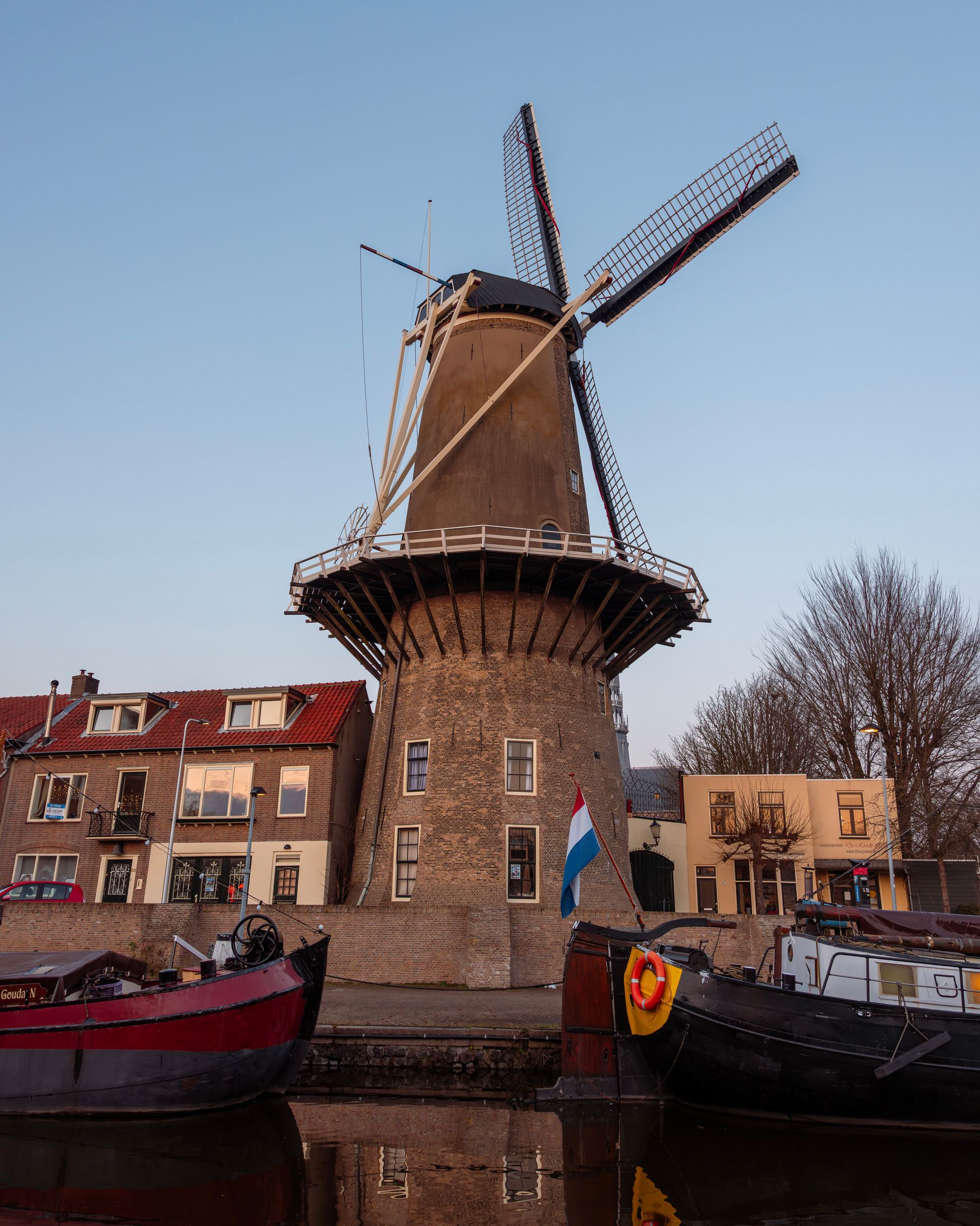 A houseboat on a Dutch canal with a windmill in the distance